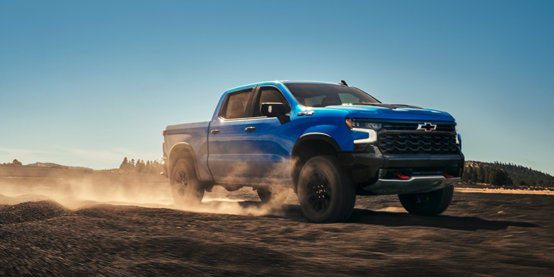 a blue 2025 Chevrolet Silverado 1500 driving on a dirt road